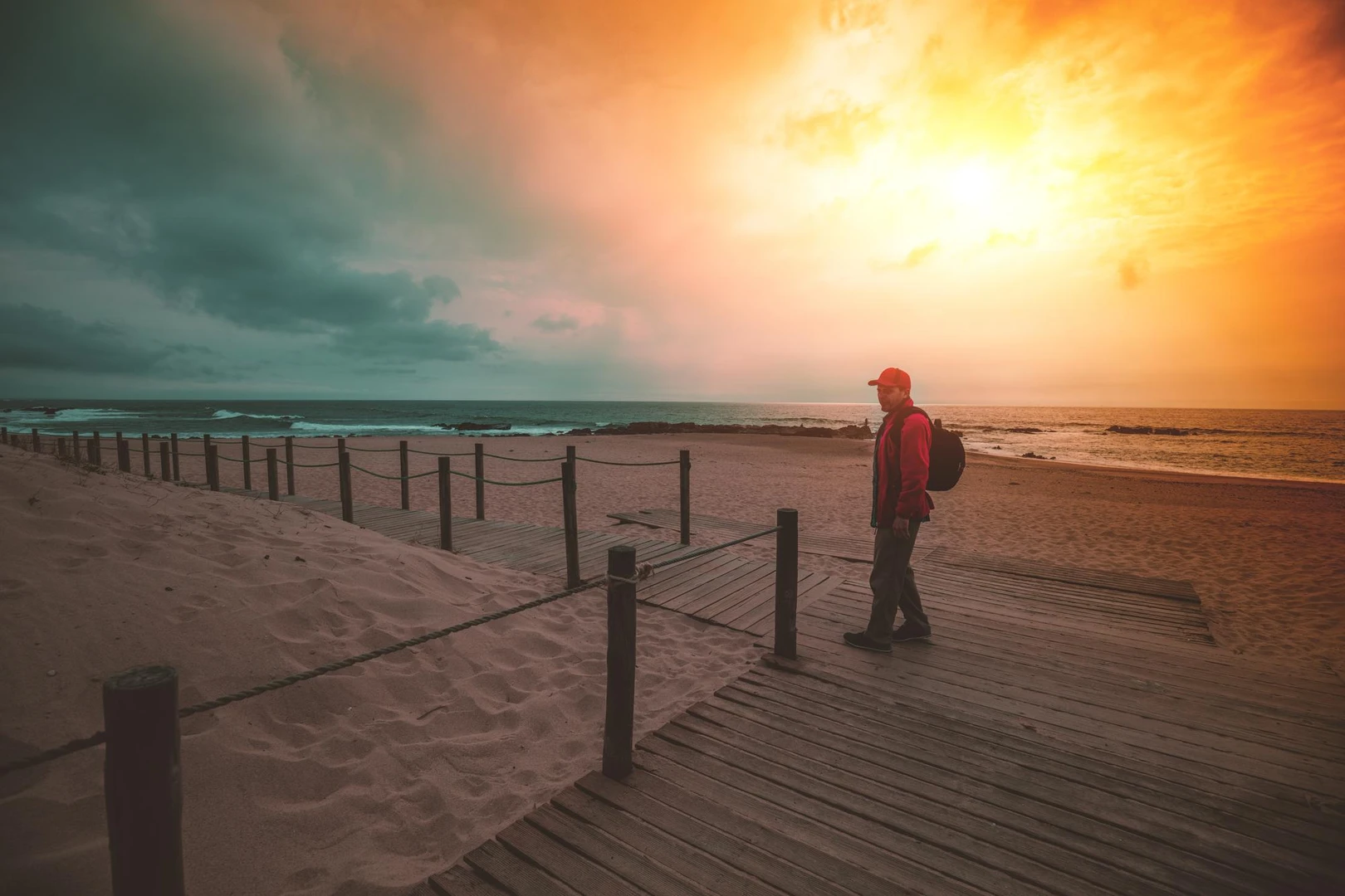 Silueta de una persona caminando hacia el mar durante el atardecer.