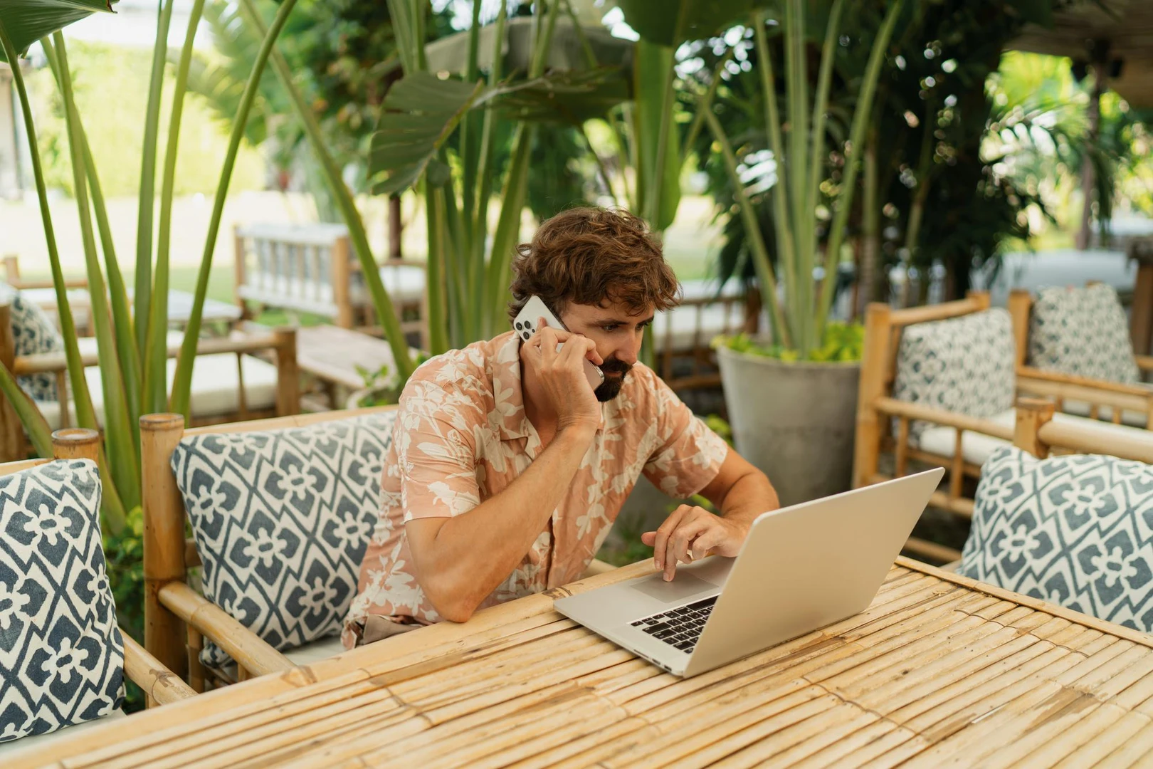 Hombre trabajando con notebook en un café al aire libre.